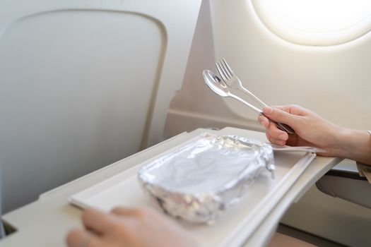 Woman with tray of food on the plane, food served on board of economy class airplane.