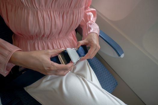 Close up of women fasten seat belt on the airplane.