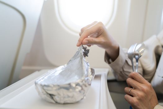 Woman with tray of food on the plane, food served on board of economy class airplane.