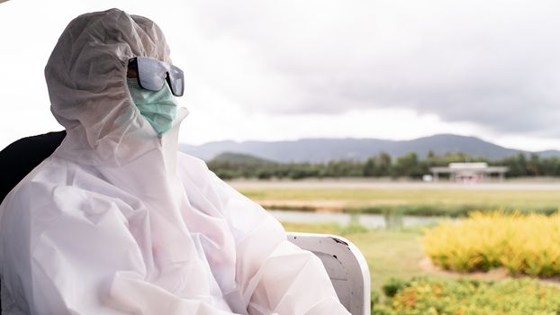 Person wearing protective suit , PPE with mask, sit on bus to entering airplane parking outside terminal in airport. during covid-19 virus pandemic , safety travel concept.