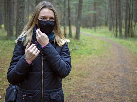 Beautiful european Women Wearing Protective Mask Outside Pretty young girl in medical black face mask in a forest. covid19 concept. modern reality. copy space. 2020, allergy. Autumn season. Copy space