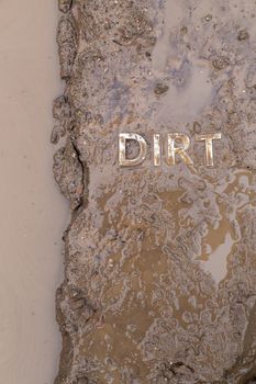 the word mud imprinted in wet dirt road surface and puddle - close-up with selective focus in flat lay perspective.