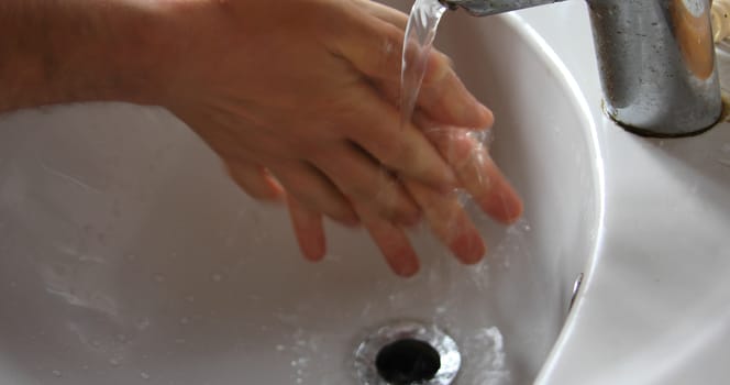 Man washes his hands thoroughly in the sink