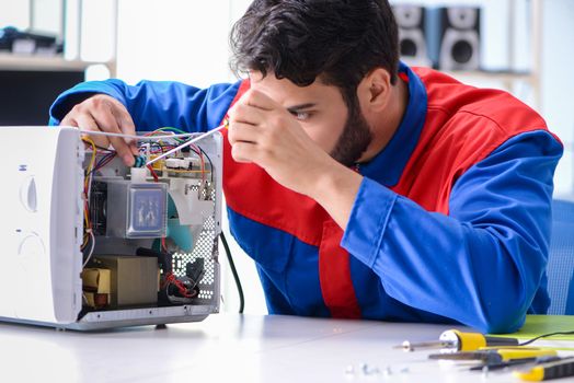 Young repairman fixing and repairing microwave oven