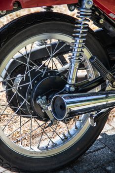 Red chrome motorcycle with spokes, exhaust and shock absorber in close-up