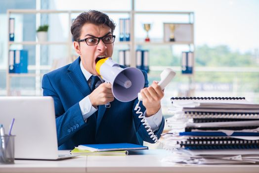 Angry aggressive businessman with bullhorn loudspeaker in office