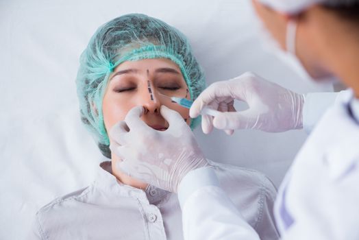 Plastic surgeon preparing for operation on woman face