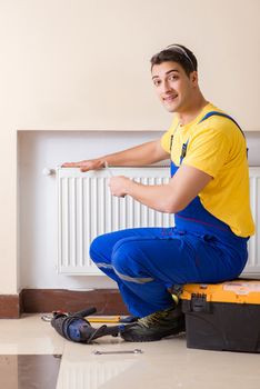 Young repairman contractor repairing heating panel 
