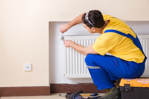 Young repairman contractor repairing heating panel 