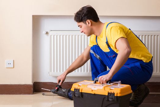 Young repairman contractor repairing heating panel 