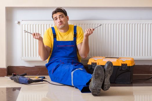 Young repairman contractor repairing heating panel 