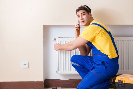 Young repairman contractor repairing heating panel 