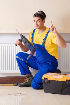 Young repairman contractor repairing heating panel 