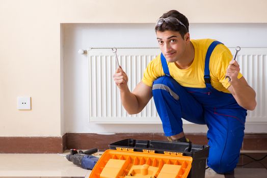 Young repairman contractor repairing heating panel 