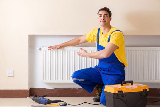 Young repairman contractor repairing heating panel 