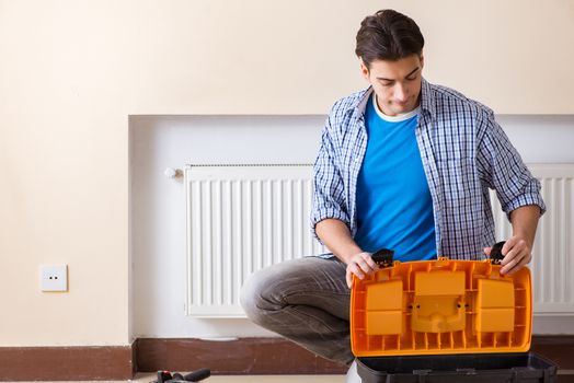 Young repairman contractor repairing heating panel 
