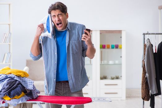 Young man husband doing clothing ironing at home