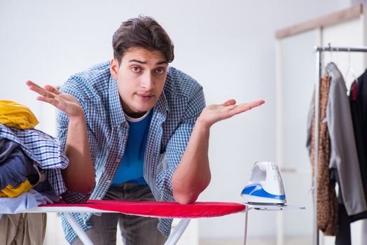 Young man husband doing clothing ironing at home