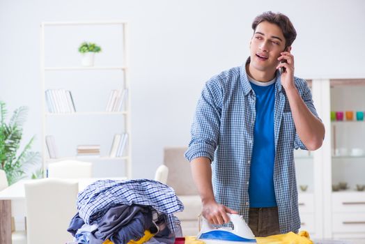 Young man husband doing clothing ironing at home