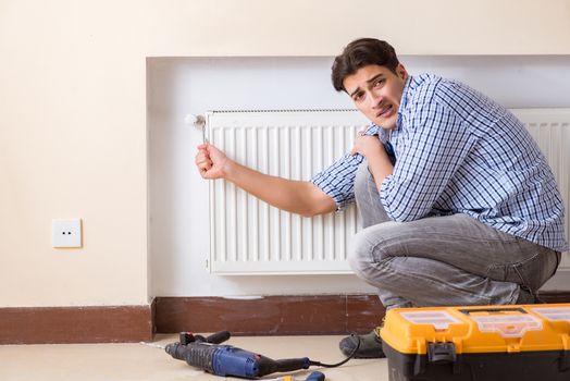 Young repairman contractor repairing heating panel 