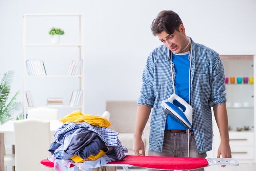 Young man husband doing clothing ironing at home