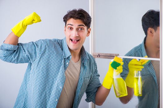 Young man cleaning mirror at home hotel