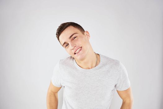 Man in a white t-shirt emotions gestures with hands close-up cropped view light background. High quality photo