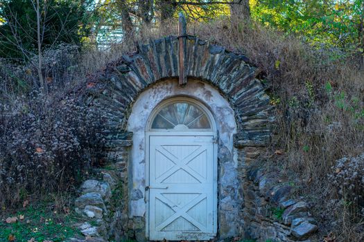 An Old Wooden Door in a Cobblestone Arch Leading Into a Bunker Underneath a Hill