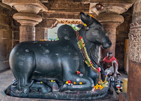 Hampi,Karnataka,India:November 6th, 2018-Huge black stone Nandi and priest in shrine near Virupaksha temple.