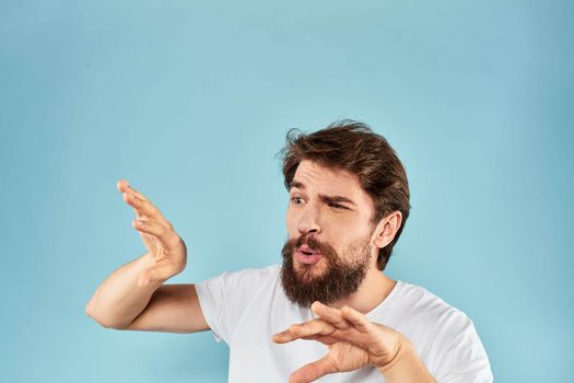 Emotional man with a beard in a white t-shirt blue background fun lifestyle. High quality photo