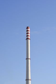 Red and white heating plant chimney against blue sky