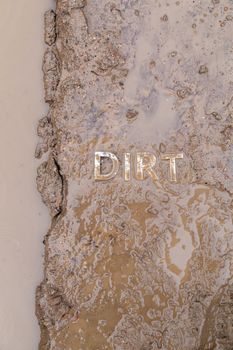 the word mud imprinted in wet dirt road surface and puddle - close-up with selective focus in flat lay perspective.