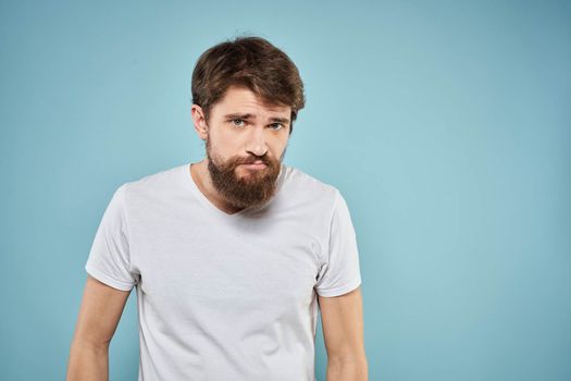 Man in white t-shirt emotions facial expression cropped view studio blue background lifestyle. High quality photo