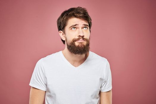 emotional man white t shirt sad facial expression pink background. High quality photo