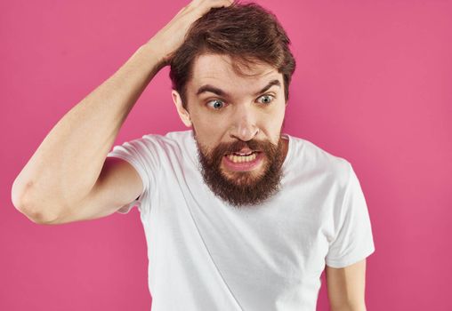 An angry man with a bushy beard bared his teeth against a pink background. High quality photo