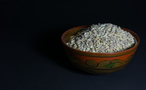 Uncooked pearl barley in a ceramic bowl with russian folk patterns