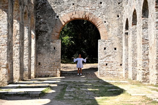 Young girl exploring an ruins of ancient city of Butrint.Olive-shaded archaeological site home to the Greek, Roman & medieval remains of the city of Butrint.