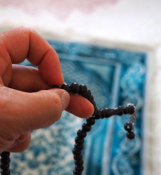 a muslim praying by drawing a rosary, a muslim drawing a close-up rosary,