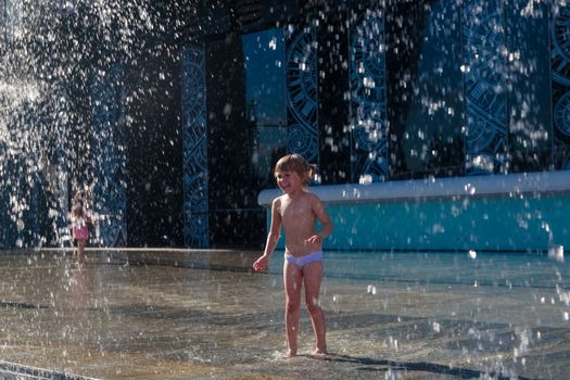 A little girl splashes water from a fountain on the territory of the Moscow city business center