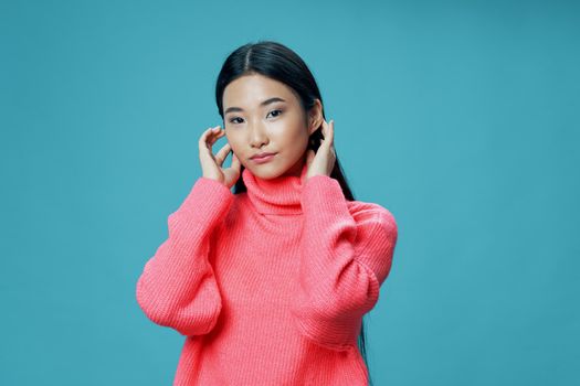 Woman in pink sweater Asian appearance straightens her hair blue background model