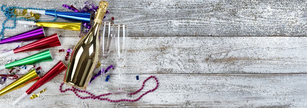 Happy New Year concept with a golden bottle of champagne, drinking glasses and party decorations 