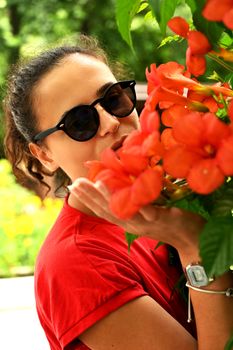 Beautiful young woman smelling red flowers in the park. Sarajevo, Bosnia and Herzegovina