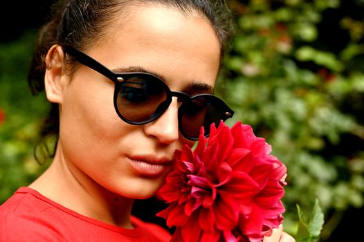 Beautiful young woman smelling red flower in the park. Sarajevo, Bosnia and Herzegovina