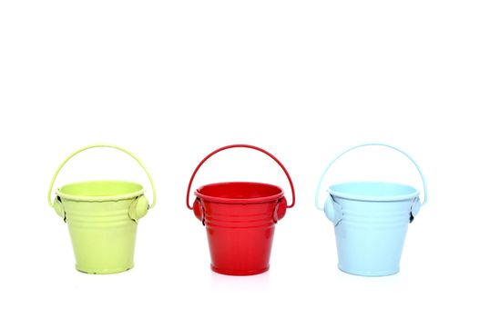 Three metal buckets of different colours with handle, isolated on white background