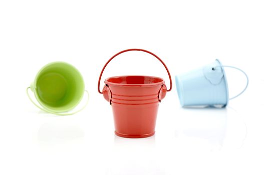 Three metal buckets of different colours with handle, isolated on white background