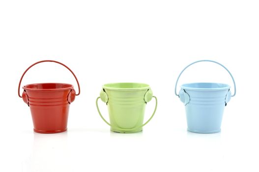 Three metal buckets of different colours with handle, isolated on white background