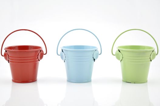 Three metal buckets of different colours with handle, isolated on white background