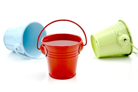 Three metal buckets of different colours with handle, isolated on white background