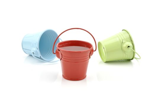 Three metal buckets of different colours with handle, isolated on white background