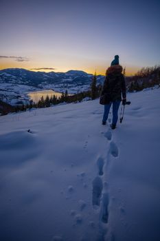 Photographers photographing winter lake mountain scene in sunset, alone in wilderness. Rovni, Valjevo, Serbia